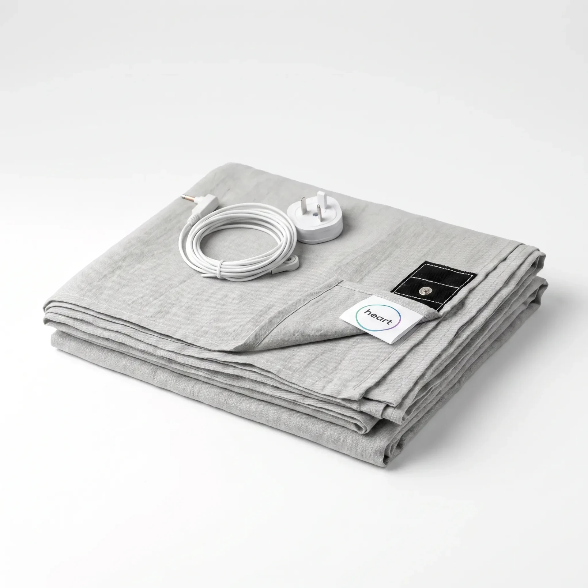 Folded light-grey Grounding Heart flat sheet with its slim cord and Australian three-pin plug